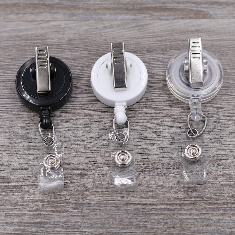 Puede incluir: Tres portagajes retr&aacute;ctiles, uno negro, uno blanco y uno transparente. Cada portagajes tiene un clip de metal y una correa de pl&aacute;stico transparente.