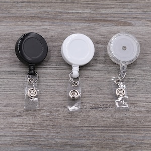 Puede incluir: Tres portagajes retr&aacute;ctiles, uno negro, uno blanco y uno transparente. Cada portagajes tiene una correa de pl&aacute;stico transparente y un clip de metal.
