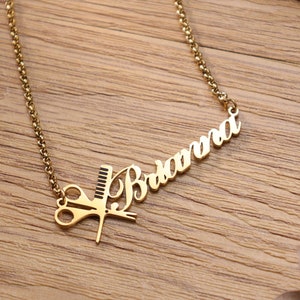 May include: Gold necklace with a nameplate that reads "Briana" and a charm of scissors and a comb.