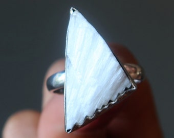May include: A silver ring with a triangular white selenite stone.