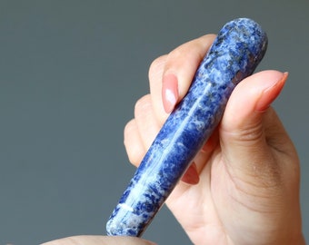 May include: A hand holds a blue and white crystal roller, a tool used for massage and relaxation.