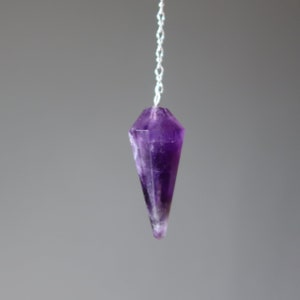 May include: A purple amethyst crystal pendulum with a silver chain.