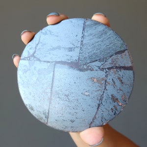 May include: A round, blue and silver decorative coaster with a cracked and textured surface.