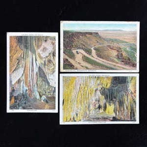 May include: Three vintage postcards with scenic views. One shows a winding road through a desert landscape, another depicts cave formations, and the third displays a different cave interior with yellow and white formations.
