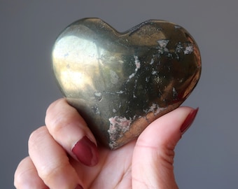 May include: A heart-shaped polished pyrite stone with a golden and brown color. The stone has a rough, textured surface.