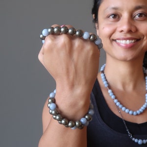 Peut inclure: Un bracelet composé de perles bleu clair et dorées. Le bracelet est porté au poignet.