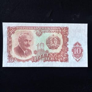 May include: A vintage Bulgarian 10 Leva banknote. The note features a portrait of a man on the left, with text in Cyrillic script. The center has a coat of arms and the number 10. The note is primarily brown and green.