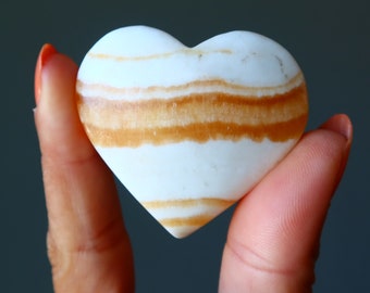 May include: White heart-shaped stone with brown stripes.