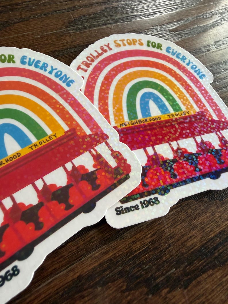 May include: Two stickers showing a red trolley design with a rainbow arch and the text "Trolley Stops For Everyone" and "Since 1968". The stickers have a glittery finish.