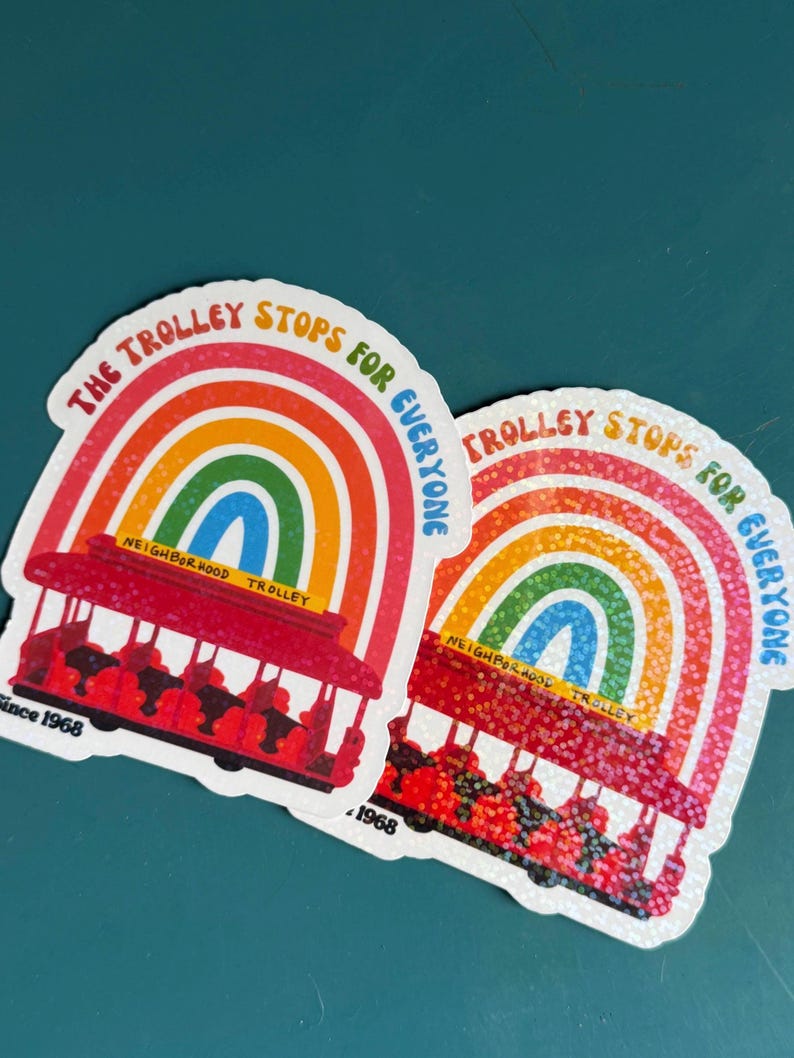 May include: Two stickers with a red trolley design, a rainbow arch, and the text "The Trolley Stops For Everyone." The stickers have a white border and the words "Neighborhood Trolley" and "Since 1968."