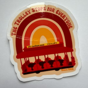 May include: A sticker featuring a red trolley with the text "THE TROLLEY STOPS FOR EVERYONE" in a semi-circular design. The trolley is set against a rainbow background with the words "NEIGHBORHOOD TROLLEY" and "Since 1968".