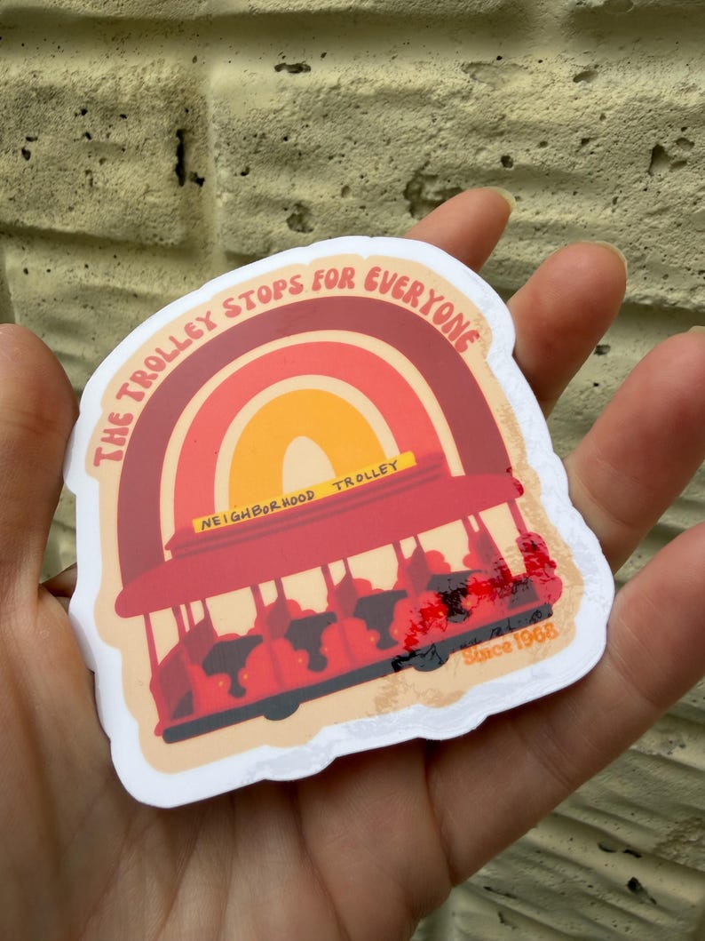 May include: A sticker featuring a red trolley with the text "The Trolley Stops for Everyone" above a rainbow design. The sticker also includes the text "Neighborhood Trolley" and "Since 1968".