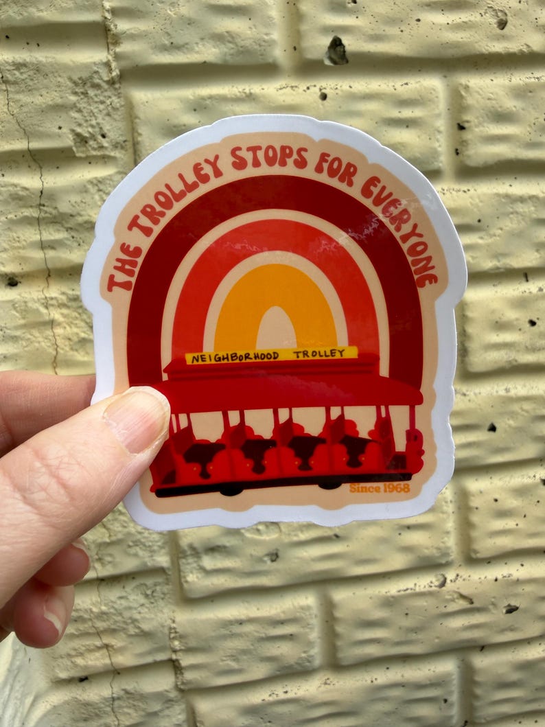 May include: A sticker with a red trolley illustration and the text "The Trolley Stops For Everyone." The design includes a rainbow arch and the words "Neighborhood Trolley" and "Since 1968."