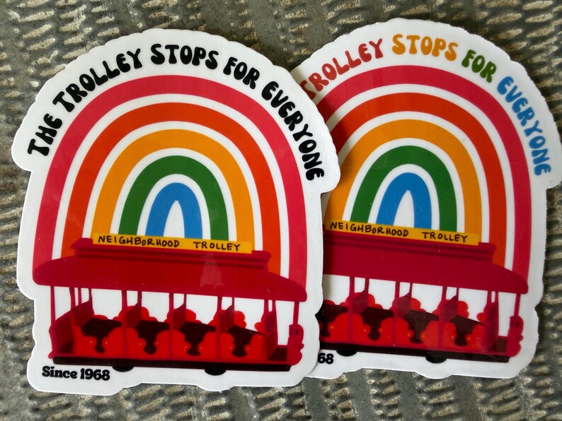 Pu&ograve; includere: Due adesivi con un design arcobaleno e un tram rosso. Il testo sugli adesivi recita "The Trolley Stops for Everyone" e "Neighborhood Trolley". Gli adesivi includono anche il testo "Since 1968".