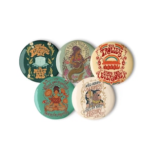 May include: Five circular pin-back buttons featuring colorful graphic illustrations and text. Designs include a mermaid playing a banjo, a trolley with a rainbow, a person meditating among sunflowers, and various slogans like What a Beautiful Day to Melt Ice.