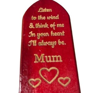 May include: Red wooden plaque with a gold inscription that reads "Listen to the wind & think of me In your heart I'll always be. Mum" with three gold hearts at the bottom.