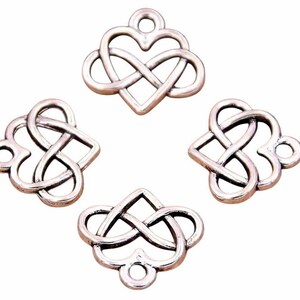 May include: Four silver-coloured charms featuring a heart and infinity knot design. Each charm has a small loop at the top for attaching to jewellery or other crafts. The charms are displayed against a white background.