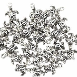 May include: A collection of small, silver-coloured turtle charms. Each charm features a detailed turtle design with a textured shell and a loop for attaching to jewellery or other crafts. The charms are scattered across a white background.