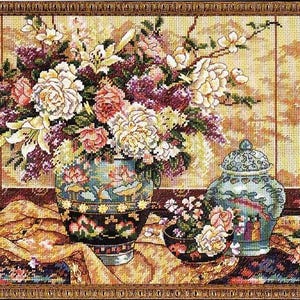 Può includere: Una natura morta con un bouquet di fiori bianchi, rosa e viola in un vaso blu e nero con un motivo floreale. Il vaso è appoggiato su una tovaglia dorata e marrone. Un vaso in porcellana blu e bianco con un coperchio si trova sul lato destro dell'immagine.