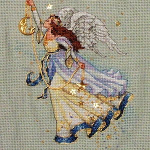 Könnte beinhalten: Eine Kreuzstich-Stickerei, die einen Engel mit Flügeln zeigt, der einen Halbmond und einen Stern hält. Der Engel trägt ein weißes Kleid mit blauen Akzenten und ist von goldenen Sternen umgeben.