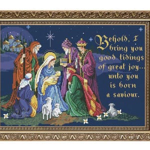 Può includere: Un ricamo a punto croce che rappresenta la scena della Natività con Maria, Giuseppe e il bambino Gesù. La scena è ambientata su uno sfondo di cielo notturno blu con stelle e una singola stella brillante sopra la mangiatoia. Il testo "Behold, I bring you good tidings of great joy... unto you is born a saviour." è scritto in un carattere decorativo.