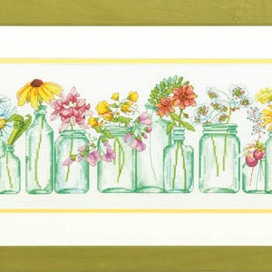 May include: A framed cross-stitch featuring a row of glass jars and bottles filled with colorful flowers. The flowers include daisies, yellow coneflowers, pink blossoms, and red blooms. The frame is a light green color.