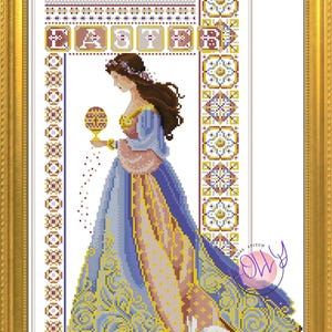 May include: A cross stitch pattern featuring a woman in a blue and gold dress holding a decorated egg. The word "Easter" is stitched above her in a banner. The background is a white fabric with a border of intricate floral designs.