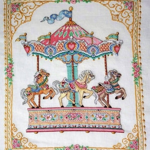 Puede incluir: Un carrusel colorido con tres caballos, un dosel rosa, azul y amarillo, y una base detallada con detalles florales.