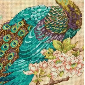 May include: A cross-stitch design of a peacock with teal, green, and purple feathers, sitting on a branch with pink flowers. The background is beige fabric, giving a vintage feel.