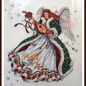 May include: A white angel with a green and red robe plays a lute. The angel has a halo and wings. The background is white with snowflakes.