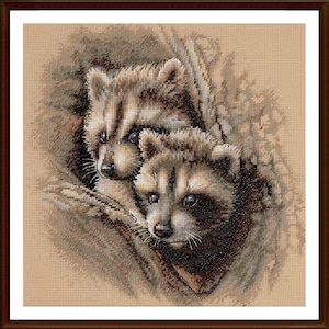 May include: A framed cross-stitch depicting two raccoons. The raccoons are rendered in shades of brown, grey, and white, with dark eyes. The background is a neutral beige, and the frame is dark brown. The artwork is a detailed piece.