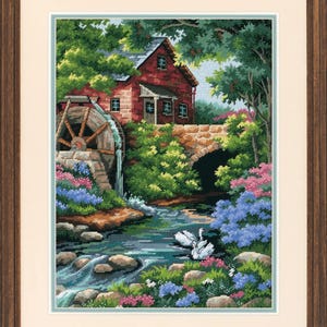 Peut inclure: Point de croix encadré représentant un paysage serein avec un moulin rouge, une roue à aubes et un pont en pierre. La scène comprend une végétation luxuriante, des fleurs colorées et un cours d'eau avec des cygnes blancs. Encadré dans un cadre en bois brun.