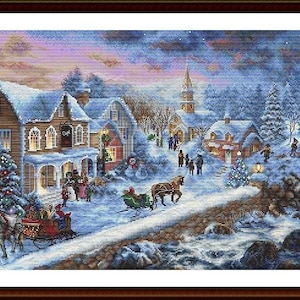 May include: A framed cross-stitch depicting a winter village scene. Snow-covered houses and trees are illuminated by Christmas lights. Horse-drawn sleighs travel along a snowy path, and a lighthouse stands in the distance under a starry sky.