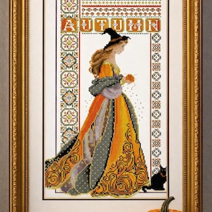 Può includere: Un ricamo a punto croce incorniciato che raffigura una persona con un cappello da strega e un abito arancione e grigio, che tiene in mano una piccola sfera arancione. La parola AUTUMN è ricamata in alto. Il design include bordi verticali e un gatto nero.