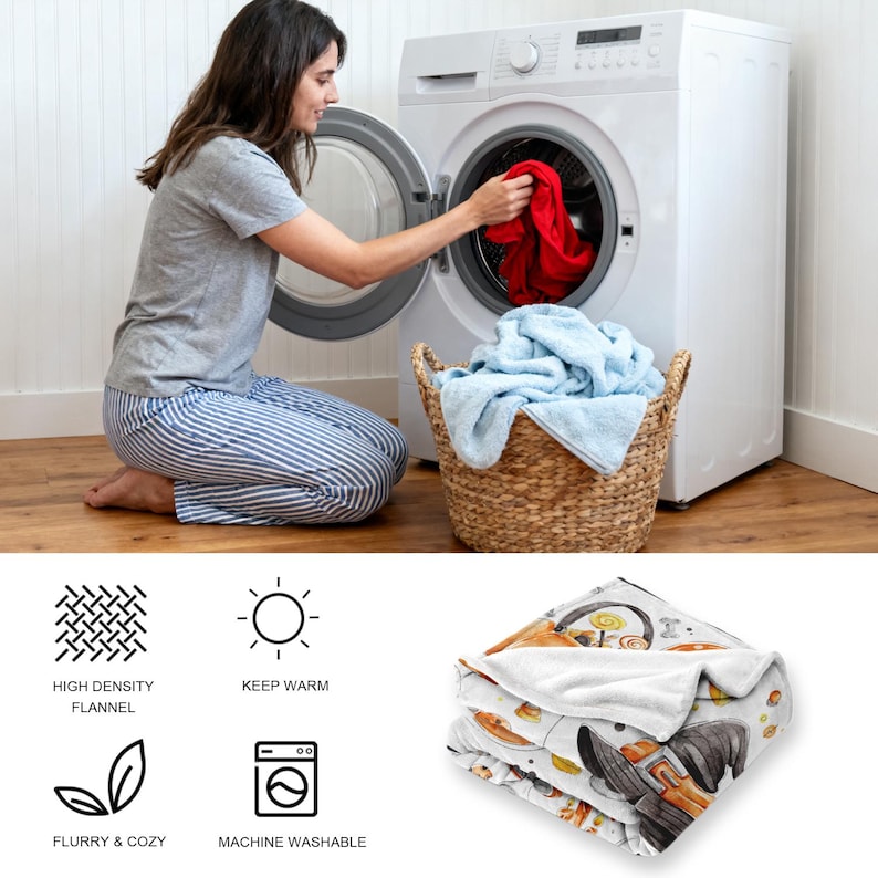 Op de afbeelding: Een persoon stopt een rood item in een witte wasmachine. Een rieten mand bevat blauwe handdoeken. Een opgevouwen witte deken met een Halloween-thema wordt getoond, met pictogrammen voor flanel, warmte en machinewasbaarheid.