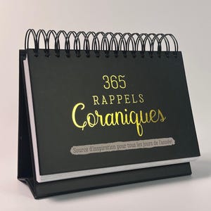 Puede incluir: Un calendario de escritorio de espiral negro con letras doradas que dicen "365 Rappels Coraniques" y "Source d'inspiration pour tous les jours de l'année!"