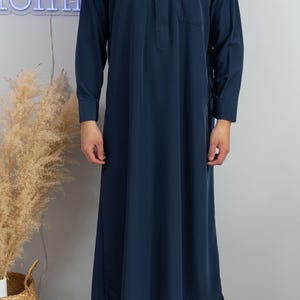 Op de afbeelding: Een donkerblauwe, lange, lange mouwen met een staande kraag en een enkele knoopsluiting. De robe heeft een zak aan de linkerkant en een zijsplit aan de rechterkant.
