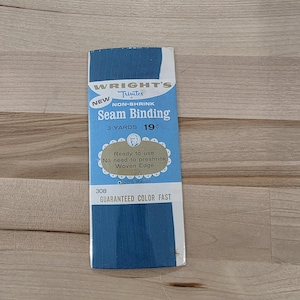 Könnte beinhalten: Eine Packung blaues, nicht einlaufendes Nahtband von Wright's Trimtex aus 100% Viskose. Die Verpackung enthält den Text: New, 3 Yards, 19 cents, Ready to use, No need to preshrink, Woven Edge, 308 und Guaranteed Color Fast.