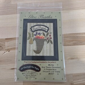 May include: A craft kit titled "Give Thanks" featuring a framed folk art design. The artwork includes a pumpkin, pears, and the words "Give Thanks." The finished size fits an 8" x 10" frame. The kit is from "All Through the Night" and made in the USA.