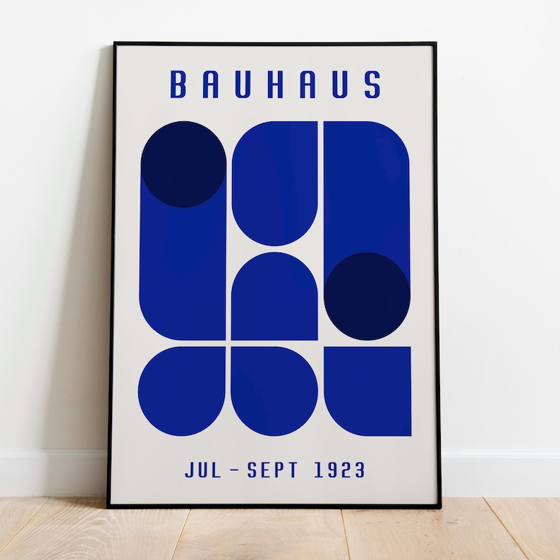 May include: A black and white poster with the text "BAUHAUS" in bold, blue letters. The poster features a geometric design of blue circles and semi-circles. The text "JUL - SEPT 1923" is at the bottom of the poster.