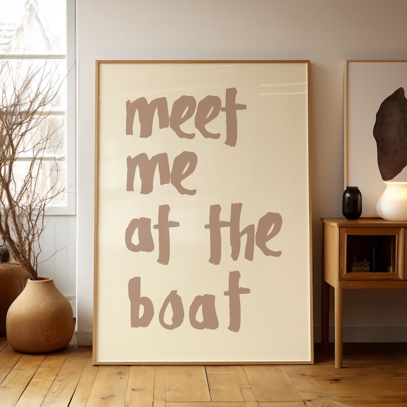 May include: A beige poster with the text "meet me at the boat" written in a brown, brushstroke font.