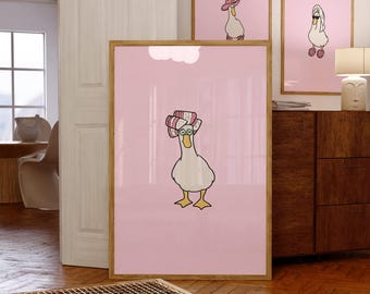 May include: Three framed art prints featuring cartoon geese on a pink background. The geese wear various accessories, including a hat, sunglasses, and curlers. The prints are displayed in a room with wooden floors and furniture.