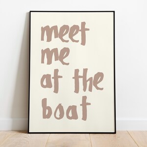 May include: A framed print with a white background and brown text that reads "meet me at the boat".