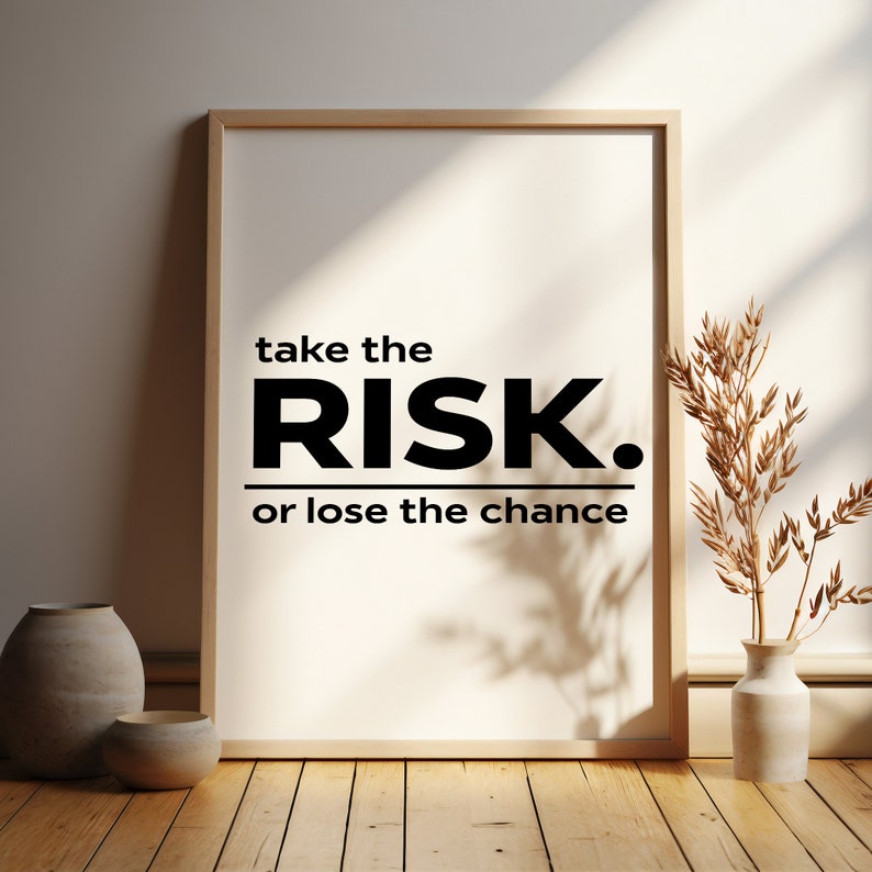 Peut inclure: Une impression encadr&eacute;e avec une citation motivante : "take the RISK. or lose the chance". L'impression est sur un fond blanc avec du texte noir. Le cadre est en bois clair et repose sur un sol en bois.