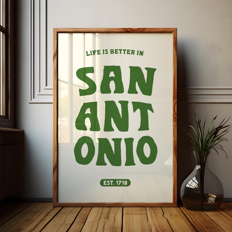 Puede incluir: Una impresi&oacute;n enmarcada con fondo blanco y texto verde que dice "Life is better in San Antonio. Est. 1718".