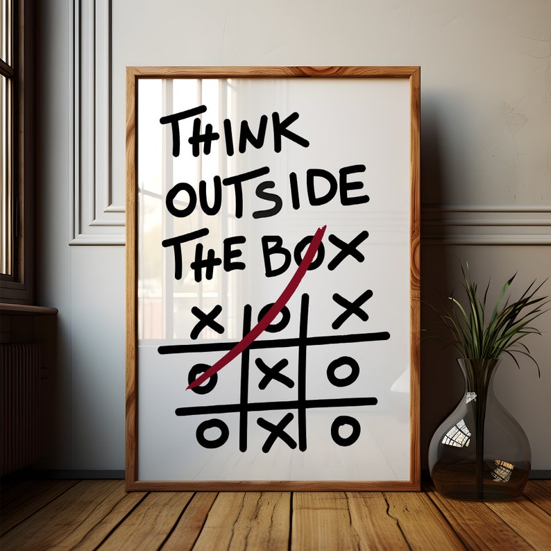 Peut inclure: Une impression encadr&eacute;e avec le texte "Think Outside The Box" &eacute;crit en marqueur noir. Une ligne rouge est trac&eacute;e &agrave; travers la bo&icirc;te dans un jeu de tic-tac-toe, avec des X et des O dans les cases.