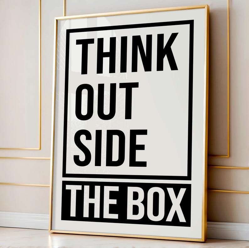 Puede incluir: Un p&oacute;ster motivacional en blanco y negro con marco dorado. El p&oacute;ster dice "Think Outside The Box".