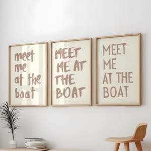 May include: Three framed prints with the text "Meet me at the boat" in a light brown color. The prints are arranged in a row on a white wall.