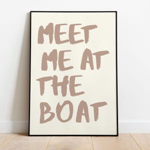 May include: A framed print with the text "Meet me at the boat" in a light brown color on a white background.