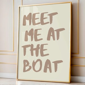 May include: A framed print with a beige background and brown text that reads "Meet me at the boat".